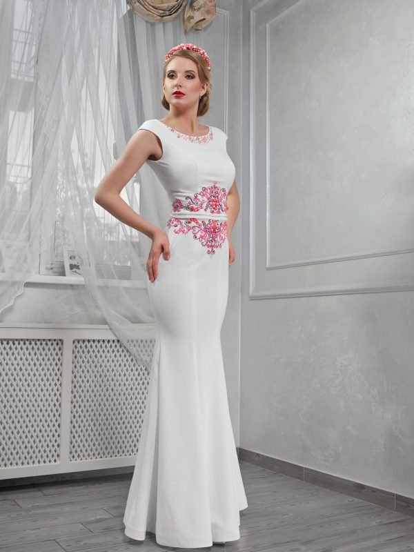 Elegant, beautiful, fashionable woman blonde in a long white dress with red embroidery, hands on hips, in room, full-length portrait, in the room, makeup.